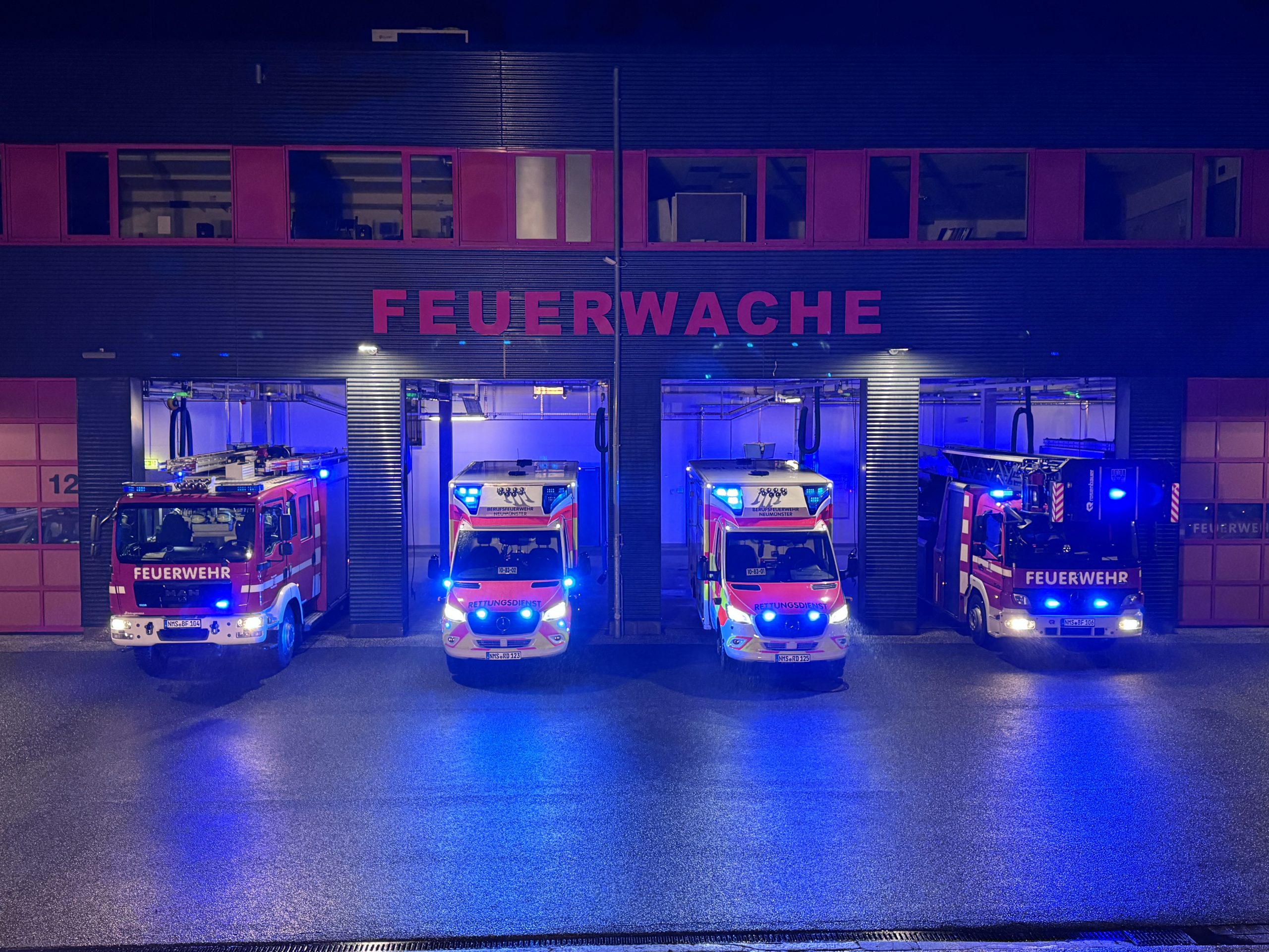 Löschfahrzeuge mit blinkendem Blaulicht vor der Feuerwache Neumünster